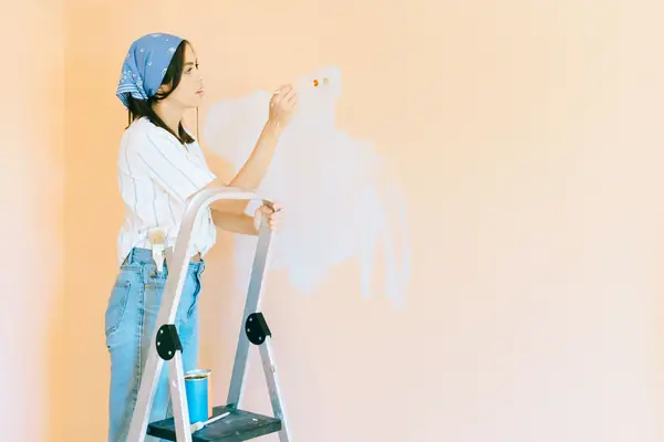 Interior painting in Toledo: painter on a stepladder rolling a wall